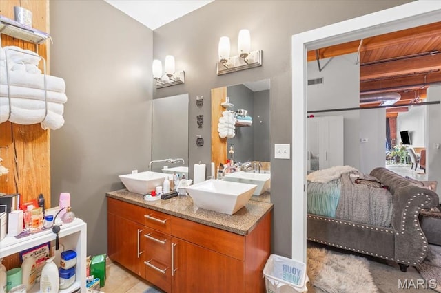 bathroom featuring connected bathroom, double vanity, and beamed ceiling
