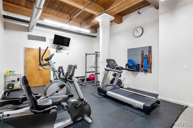 gym with decorative columns, wooden ceiling, beamed ceiling, and baseboards