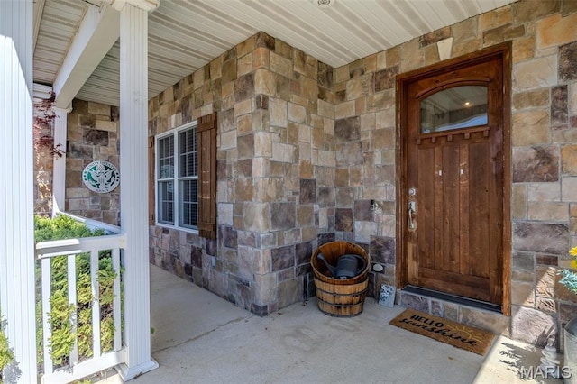 entrance to property featuring stone siding and a porch