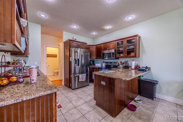 kitchen featuring appliances with stainless steel finishes, a peninsula, stone counters, glass insert cabinets, and a textured ceiling