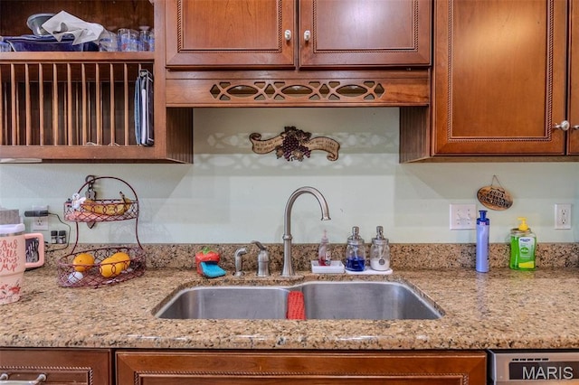 kitchen featuring a sink, light stone countertops, brown cabinets, and dishwashing machine