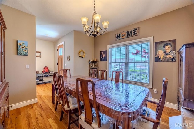 dining space with a chandelier, light wood finished floors, and baseboards