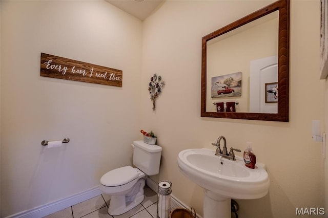 half bath with tile patterned floors, toilet, and baseboards