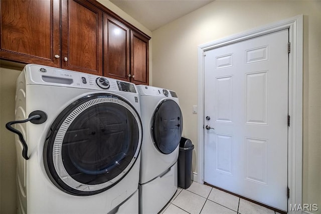 washroom featuring cabinet space, washing machine and dryer, and light tile patterned flooring