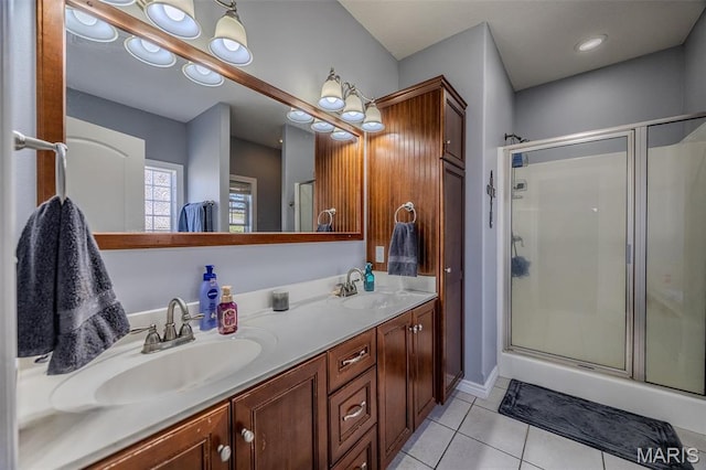 bathroom with tile patterned floors, a stall shower, double vanity, and baseboards
