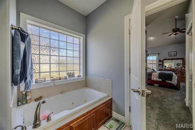 full bathroom featuring ensuite bathroom, a tub with jets, a ceiling fan, and baseboards