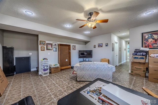 tiled living room with a textured ceiling, ceiling fan, and baseboards