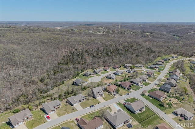 view of property location featuring a forest and nearby suburban area