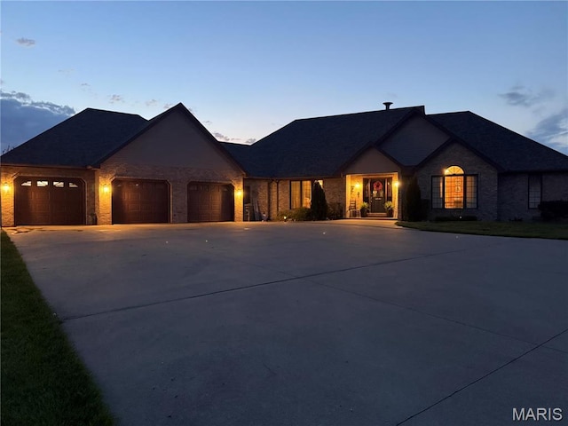 french country style house with an attached garage, driveway, and brick siding