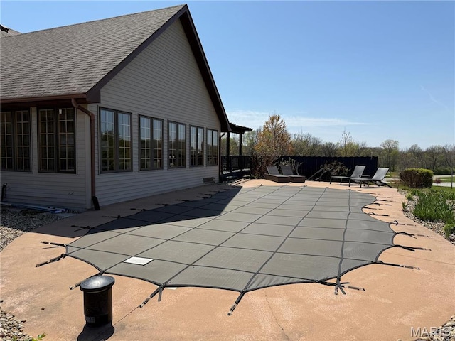 view of swimming pool with a patio area, a covered pool, and fence