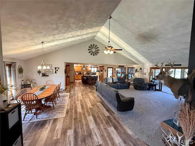 living area with vaulted ceiling, a textured ceiling, wood finished floors, a ceiling fan, and a chandelier
