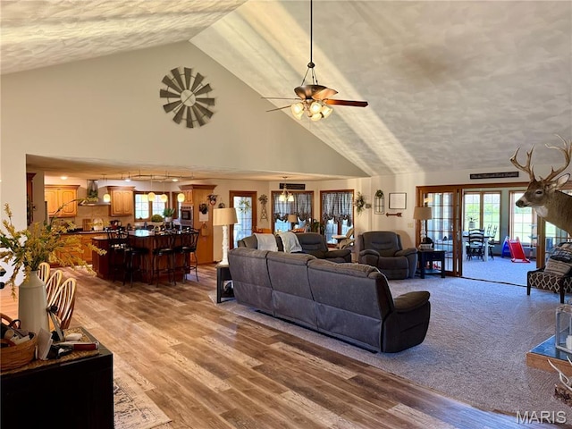 living room featuring high vaulted ceiling, a textured ceiling, light wood finished floors, and ceiling fan