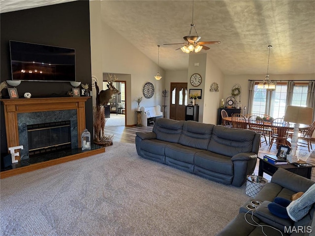 carpeted living area featuring vaulted ceiling, ceiling fan, a premium fireplace, and a textured ceiling