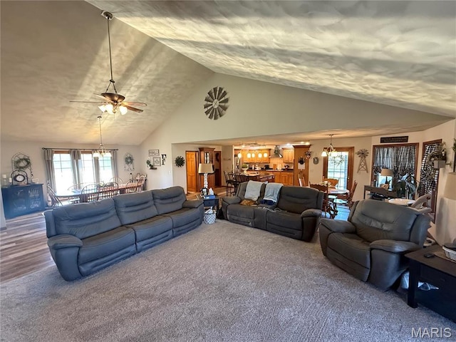 living area with a chandelier, lofted ceiling, carpet floors, and healthy amount of natural light