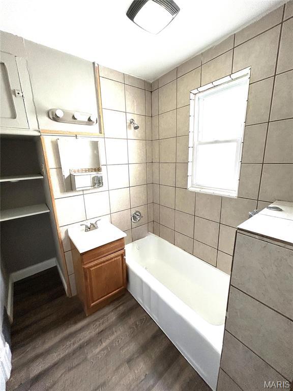 102 E 1st St, Waterloo, IL 62298 - bathroom with wood finished floors, tile walls, bathing tub / shower combination, and vanity