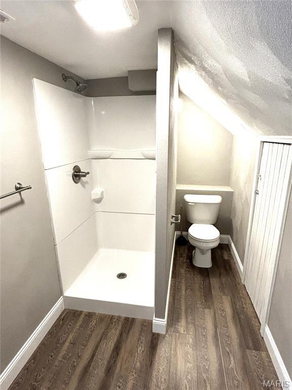 102 E 1st St, Waterloo, IL 62298 - full bath featuring wood finished floors, a stall shower, toilet, baseboards, and a textured ceiling