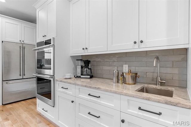 9870 E Concord Rd, Saint Louis, MO 63128 - kitchen with appliances with stainless steel finishes, a sink, light wood-type flooring, white cabinets, and light stone counters