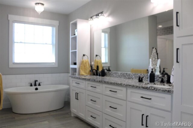 303 Orange Bowl Dr, Cape Girardeau, MO 63701 - bathroom featuring double vanity, wood finished floors, a freestanding bath, and tile walls