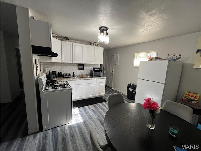 102 W Adams Dr, Cahokia, IL 62206 - kitchen featuring appliances with stainless steel finishes, ventilation hood, dark wood finished floors, light countertops, and white cabinetry