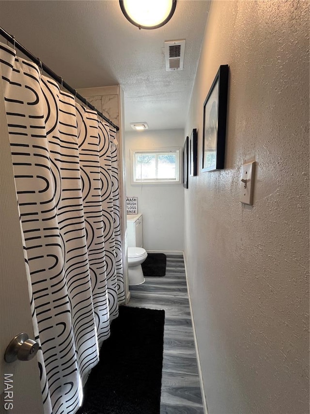 102 W Adams Dr, Cahokia, IL 62206 - bathroom featuring wood finished floors, a textured ceiling, a textured wall, and a shower with curtain