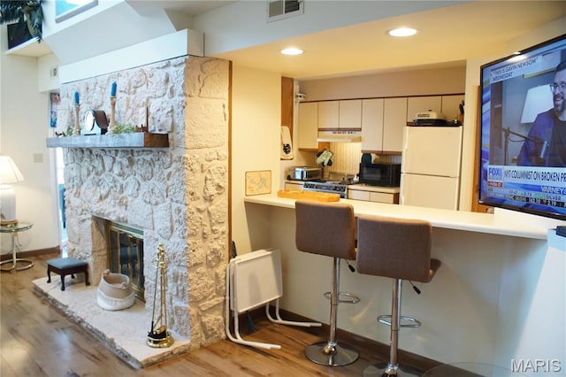64 W Windjammer Ct Unit 2D, Lake Ozark, MO 65049 - kitchen featuring freestanding refrigerator, under cabinet range hood, wood finished floors, gas range, and black microwave