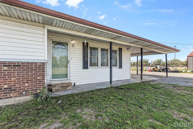 rear view of property with a carport, a lawn, and entry steps