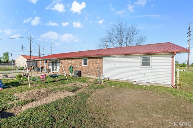 rear view of house with central AC, metal roof, and fence