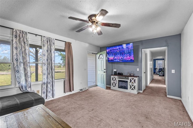 living area featuring a ceiling fan, carpet, a textured ceiling, and baseboards