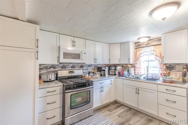 712 Nickey St, Poplar Bluff, MO 63901 - kitchen featuring white microwave, gas stove, a sink, light countertops, and white cabinetry