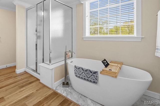full bathroom with baseboards, a stall shower, wood finished floors, crown molding, and a freestanding bath