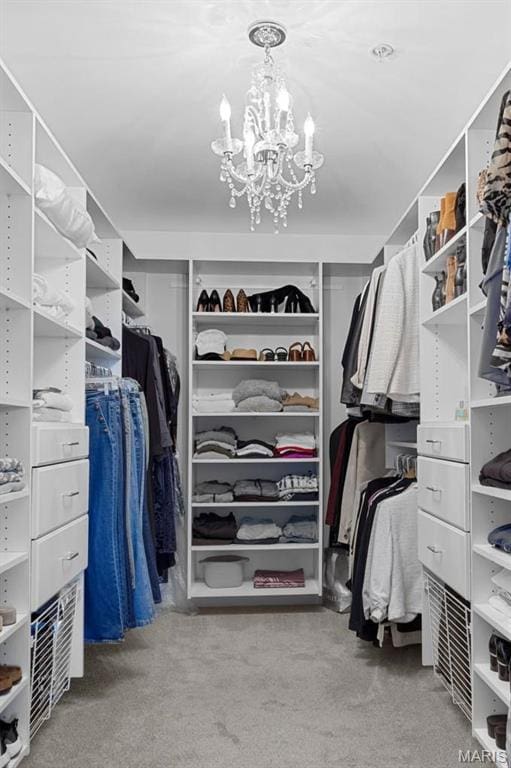 spacious closet with a chandelier and carpet flooring