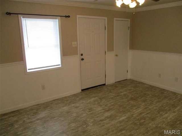 unfurnished room featuring a ceiling fan, a wainscoted wall, wood finished floors, and ornamental molding