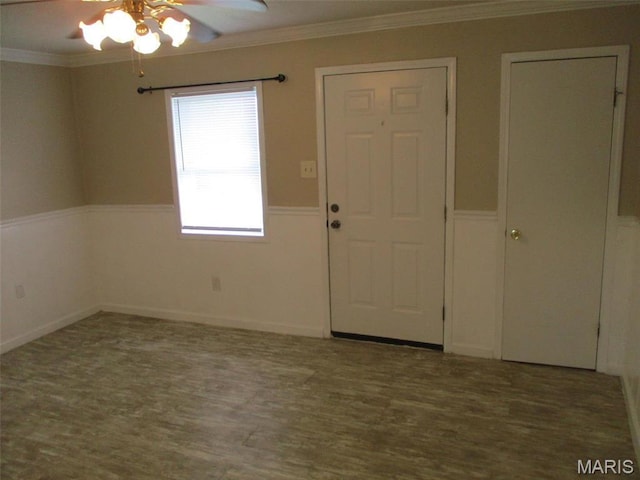 entryway featuring a ceiling fan, wainscoting, wood finished floors, and ornamental molding