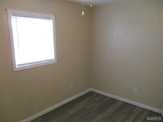spare room featuring dark wood-type flooring and baseboards