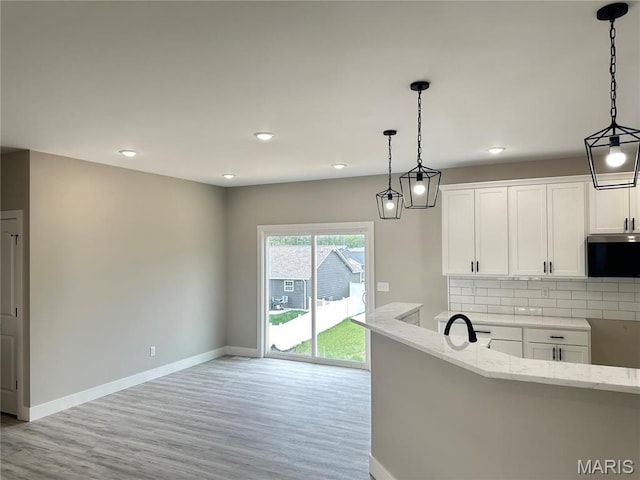 208 Pacific Ave, Union, MO 63084 - kitchen featuring light stone countertops, baseboards, stainless steel microwave, tasteful backsplash, and light wood-type flooring