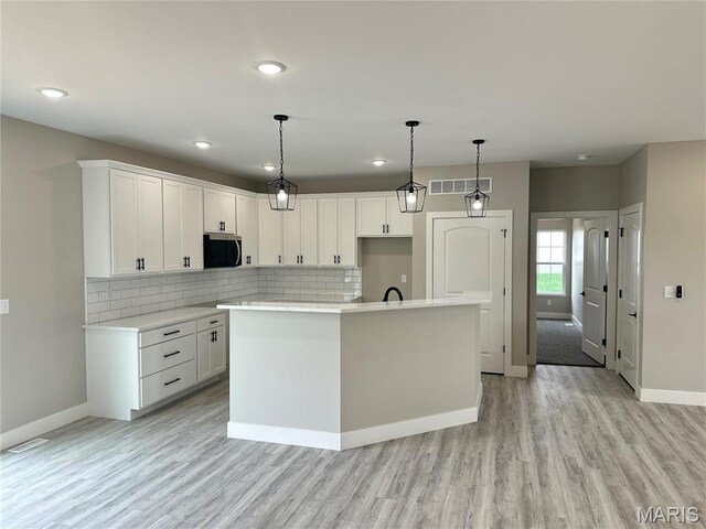 208 Pacific Ave, Union, MO 63084 - kitchen with baseboards, light wood finished floors, an island with sink, white cabinets, and recessed lighting