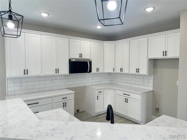 208 Pacific Ave, Union, MO 63084 - kitchen featuring stainless steel microwave, light stone countertops, tasteful backsplash, white cabinetry, and recessed lighting