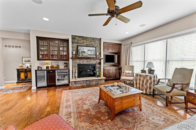 9906 Sappington Rd, Saint Louis, MO 63128 - living area with beverage cooler, a ceiling fan, wood finished floors, a stone fireplace, and baseboards