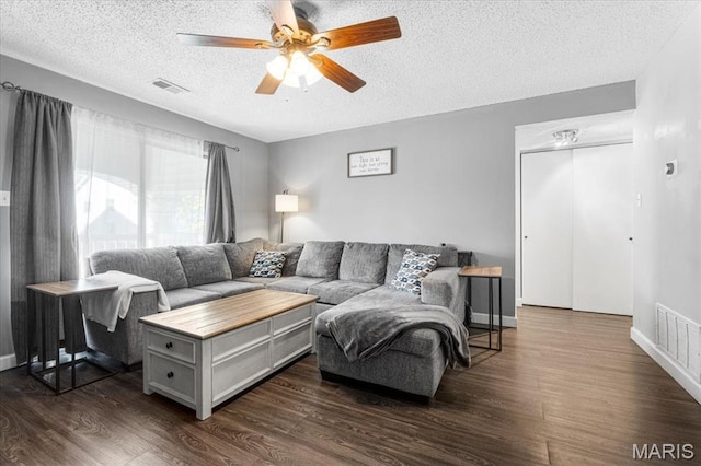 living area with a textured ceiling, ceiling fan, dark wood-style floors, and baseboards