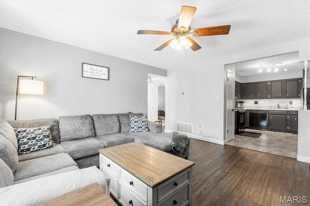 living area with a ceiling fan, dark wood-style floors, a textured ceiling, and baseboards