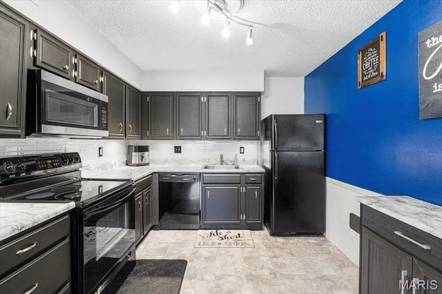 kitchen with black appliances, a textured ceiling, a sink, dark cabinetry, and backsplash