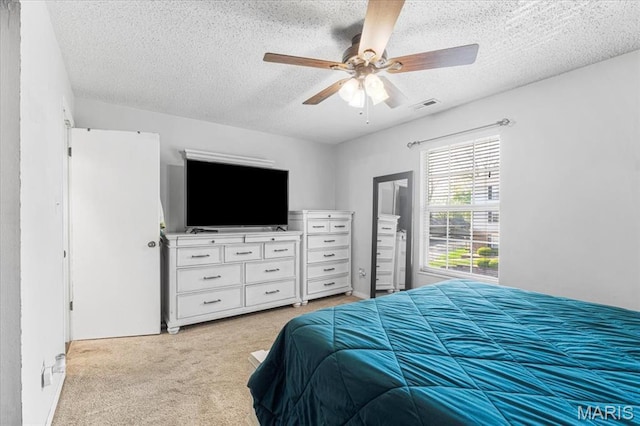 bedroom with light carpet, a textured ceiling, and a ceiling fan