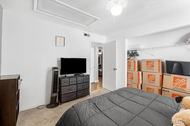 bedroom featuring a textured ceiling, attic access, and carpet