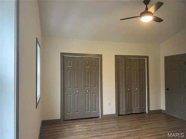 1512 36th St, Hannibal, MO 63401 - unfurnished bedroom featuring two closets, wood finished floors, baseboards, lofted ceiling, and ceiling fan