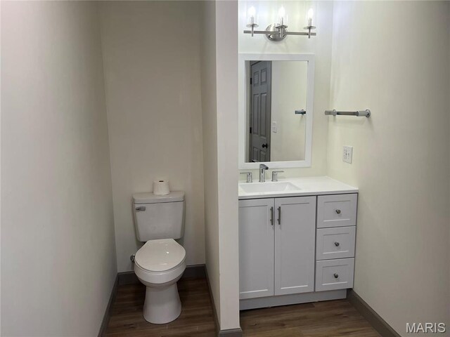 1512 36th St, Hannibal, MO 63401 - half bath featuring wood finished floors, toilet, vanity, and baseboards
