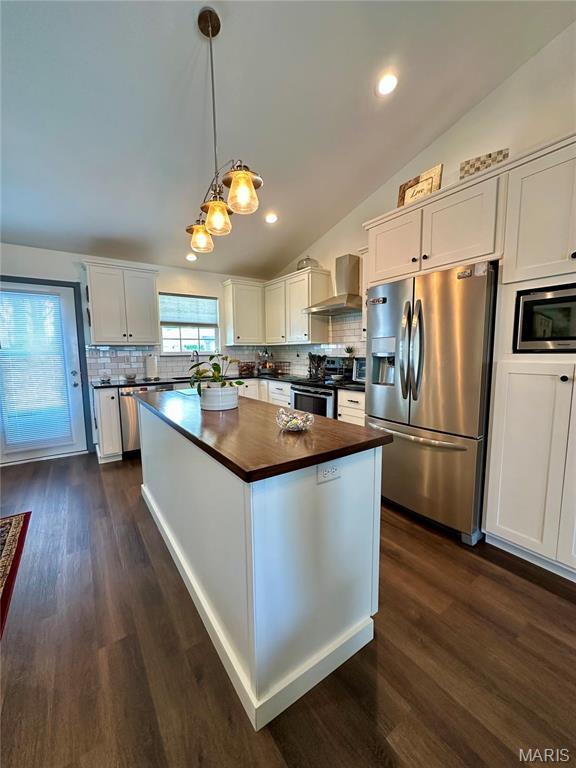 kitchen with appliances with stainless steel finishes, vaulted ceiling, decorative backsplash, white cabinets, and recessed lighting