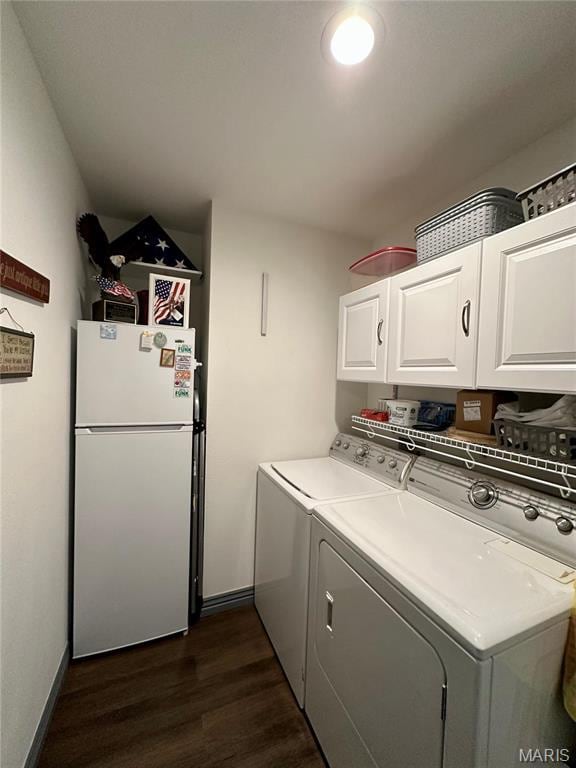 washroom featuring cabinet space, washer and clothes dryer, dark wood-type flooring, and baseboards