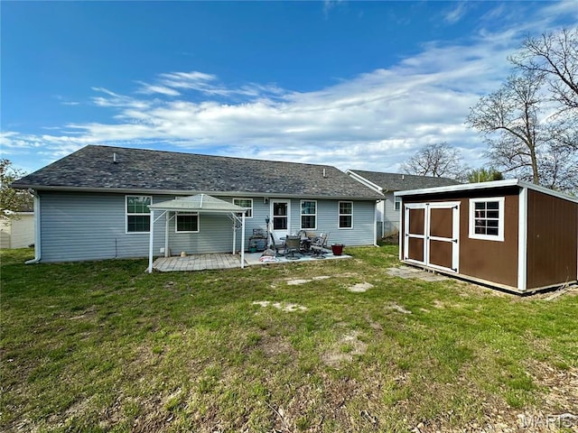 rear view of house featuring a storage unit, a yard, an outdoor structure, and a patio