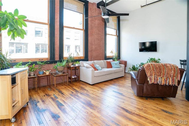 1520 Washington Ave Unit 604, Saint Louis, MO 63103 - living room featuring light wood-type flooring, ceiling fan, brick wall, and a towering ceiling