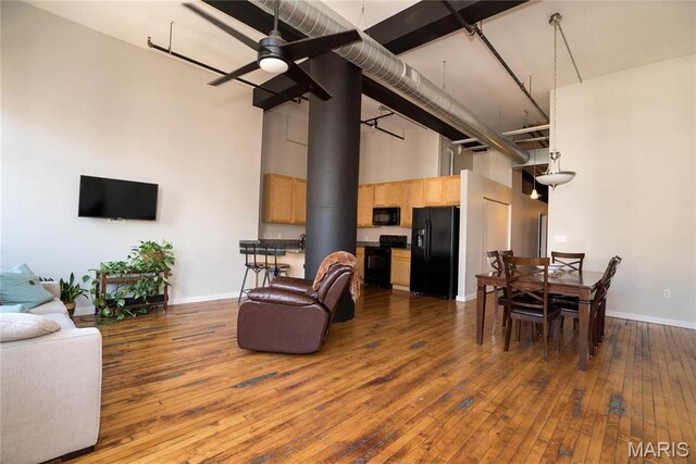 1520 Washington Ave Unit 604, Saint Louis, MO 63103 - living room featuring a towering ceiling, hardwood / wood-style floors, baseboards, a ceiling fan, and a wood stove